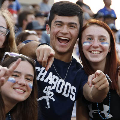 Three students in Washburn football shirts, pointing at camera and smiling