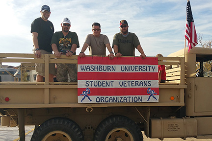 Washburn Student Military and Veteran Organization members standing in a military vehicle