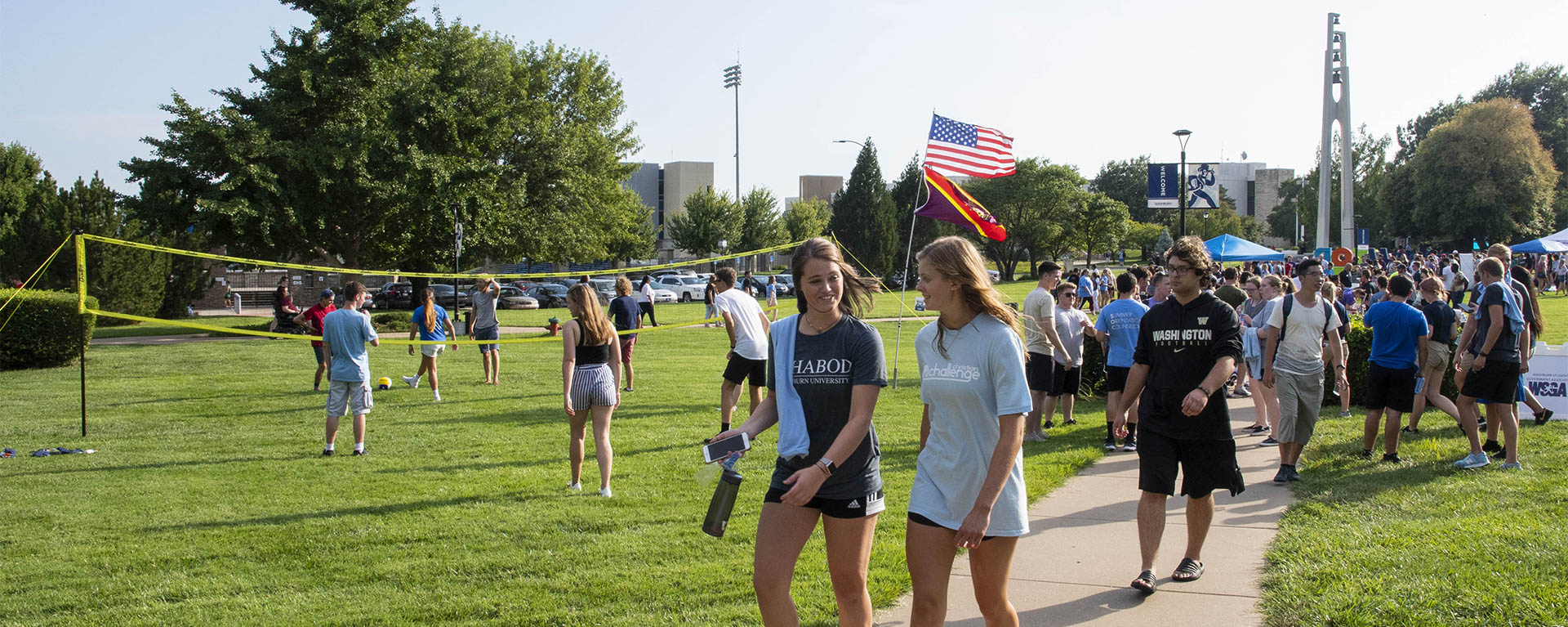 Students smile while walking on campus during an event.