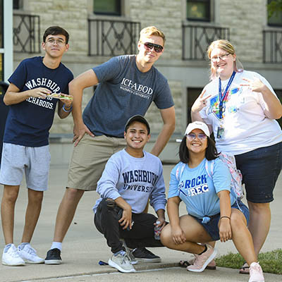 Students smile and pose for a photo at a tailgate