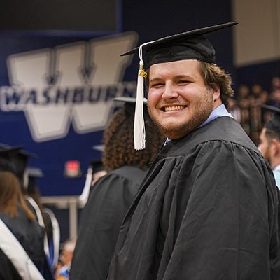 A student smiles in his cap and gown