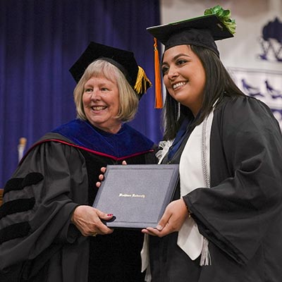 A student smiles while receiving their degree