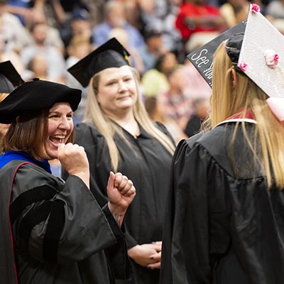 A faculty member cheers as students walk in