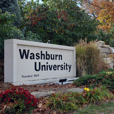 Washburn University sign by waterfall in autumn.