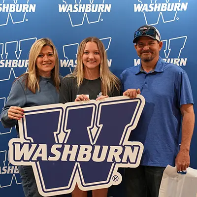 A newly admitted student poses for a #WashburnProud sign with his mom.