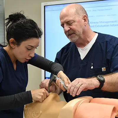 A healthcare educator helps a health science student in a lab.