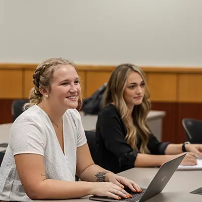 A Washburn smiles while typing notes in class.