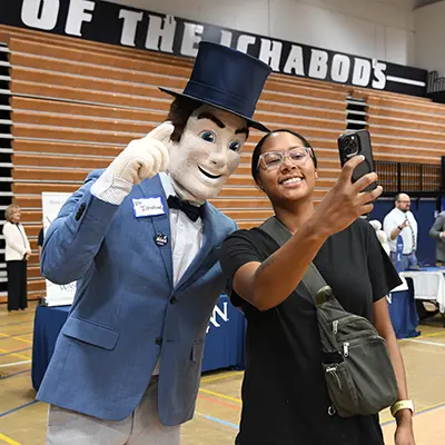 A student takes a selfie with Mr. Ichabod at a career fair.