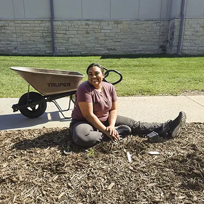 A student smiling while sitting in the garden.
