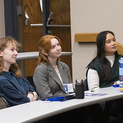 Professionally dressed students listen attentively in class.