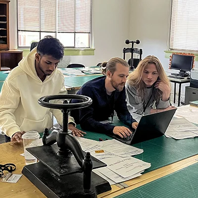 CIS students work on a project around a laptop.