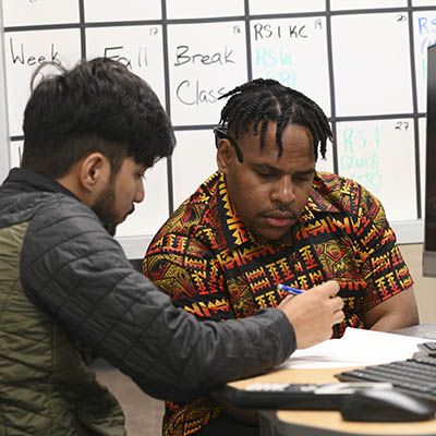 Two students work on a math assignment at a table.