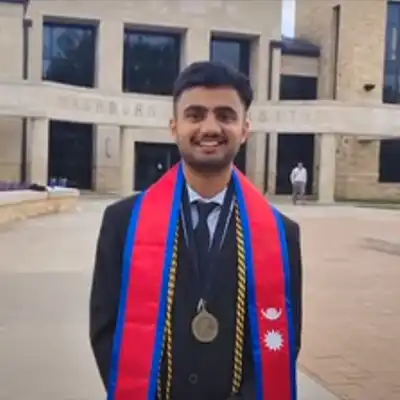 Sanskar smiles with graduation reglaia in front of Morgan Hall