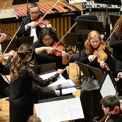 An orchestra performs on the White Concert Hall stage.