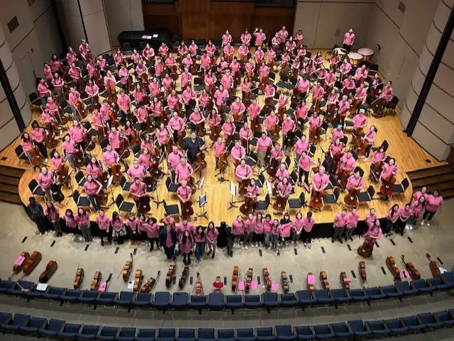 bird's eye view of stage with many cello students standing next to their cellos
