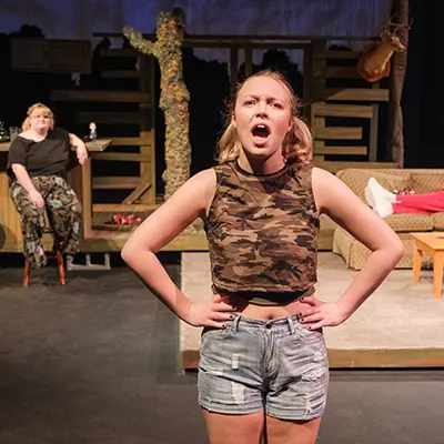 Two students sing while on stage for a production.