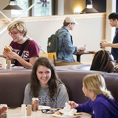 Students smile and chat over a meal in the dining hall.