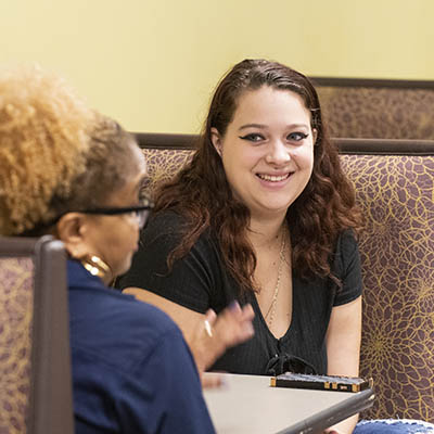 A Washburn student raises her hand while smiling during class