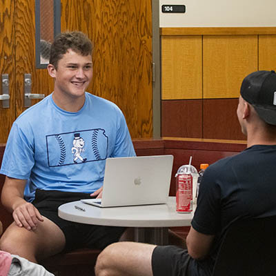 A student smiles while studying with his friend.