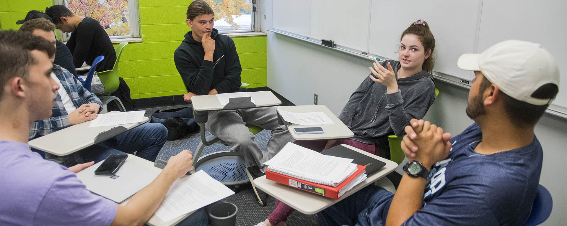 A group of communication studies students talk in a group in a classroom.