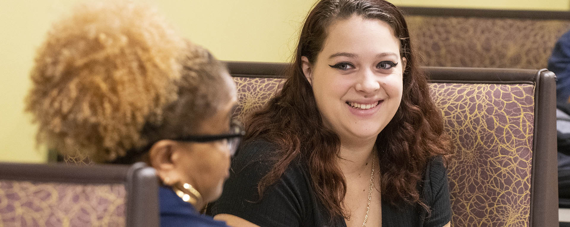 A student smiles at her advisor while talking in a study booth at Mabee Library.