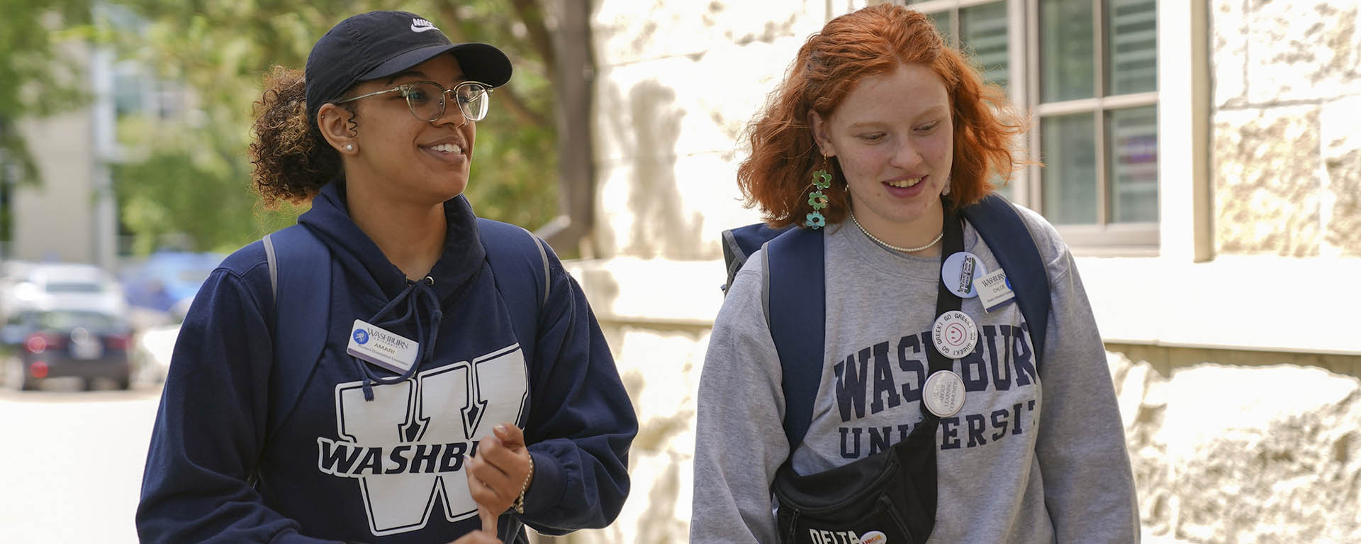 Two tour guides chat while walking on campus.