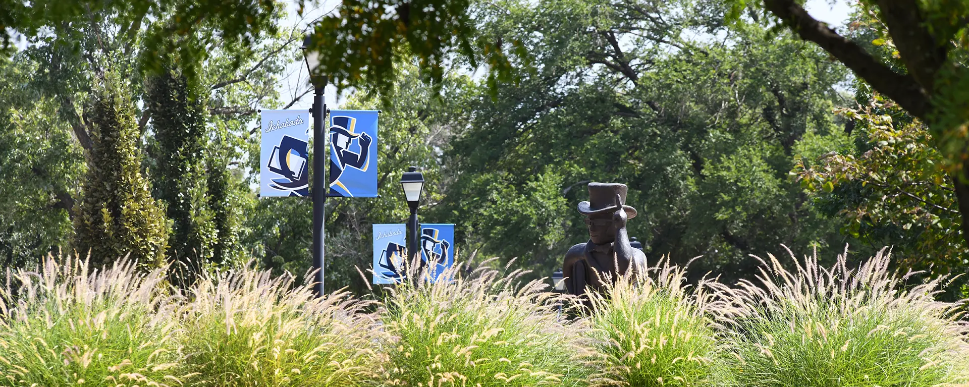 Purple flowers bloom in front of the Ichabod statue in front of Morgan Hall.