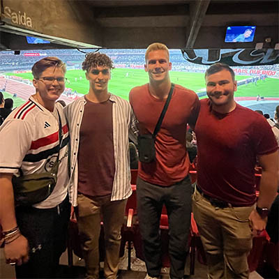 Andrew Pujado and his friends pose for a photo at a soccer stadium.