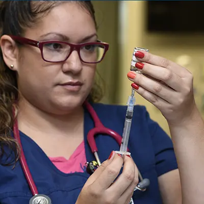 A nursing student loads a syringe.