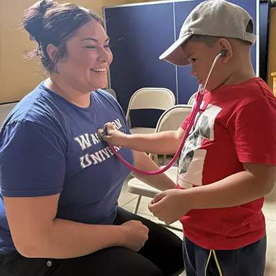 A small child listens to the heart of a nursing student with her stethoscope while studying abroad in Costa Rica.