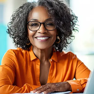 A student smiles with their laptop in front of them.