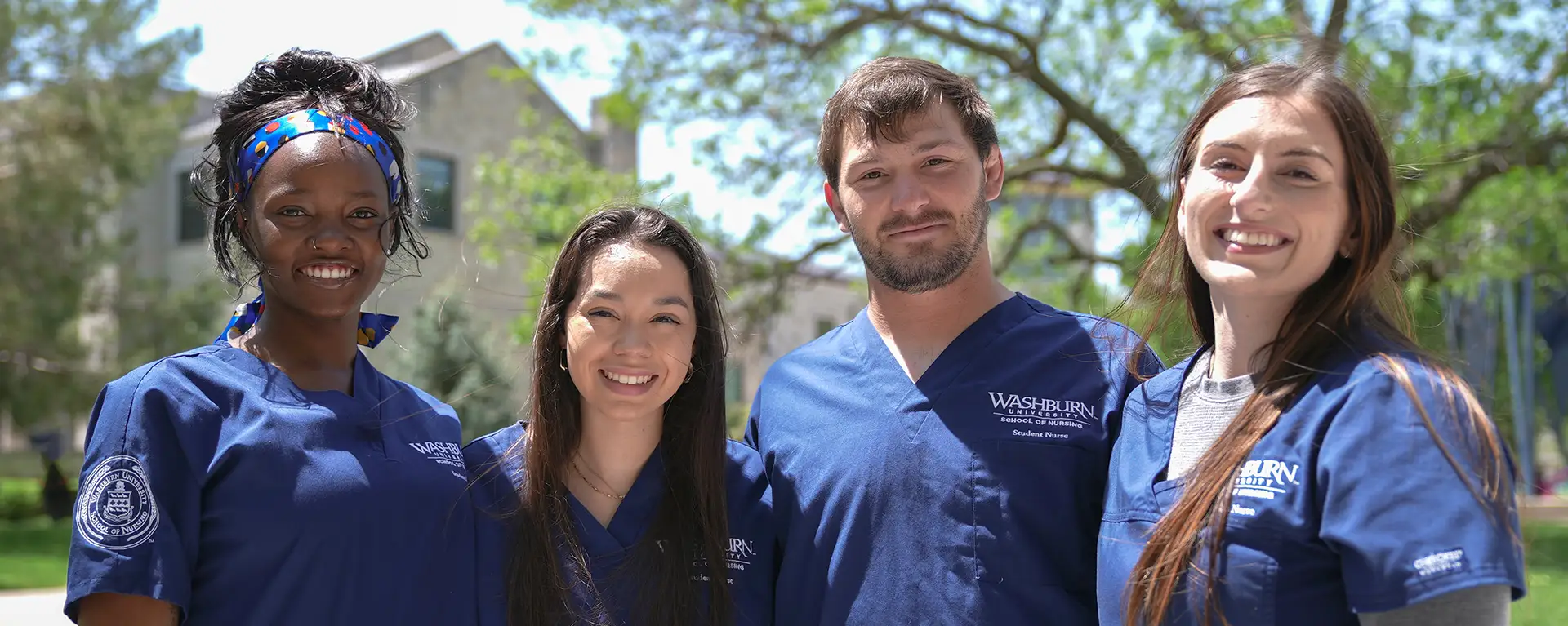 Nursing students smile for a photo while outdoors on a spring day.