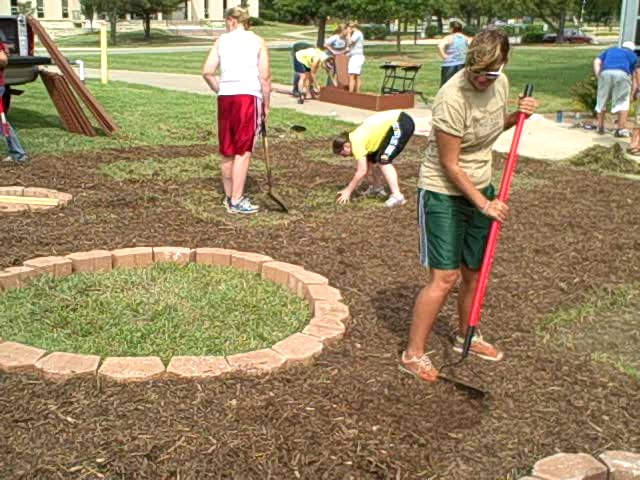 student raking dirt in a garden