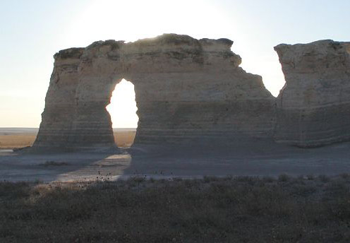 Looking through keyhole in rocks toward setting sun